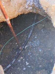 Professional copper backflow preventer installation with irrigation system and outdoor landscaping at a residential property by Advanced Irrigation & Lighting Services.