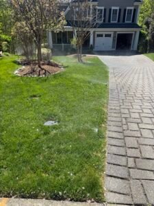 Professional copper backflow preventer installation with irrigation system and outdoor landscaping at a residential property by Advanced Irrigation & Lighting Services.
